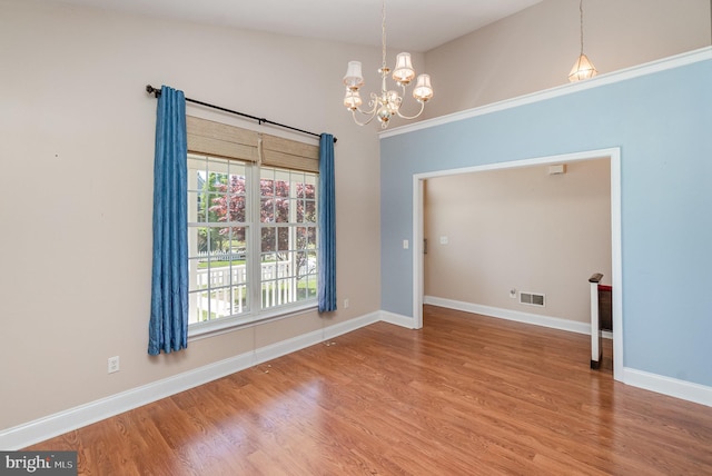 unfurnished dining area with baseboards, a notable chandelier, wood finished floors, and visible vents