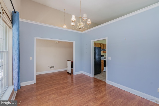 empty room featuring an inviting chandelier, light wood finished floors, baseboards, visible vents, and ornamental molding