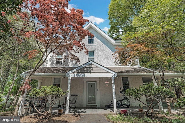 view of front of home with covered porch, a shingled roof, and stucco siding