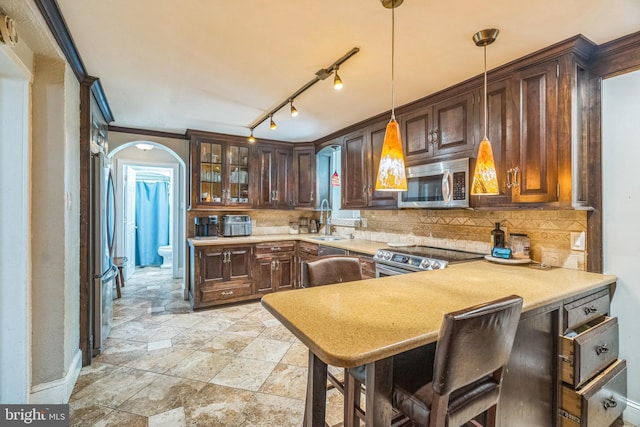 kitchen featuring a sink, arched walkways, tasteful backsplash, and stainless steel appliances