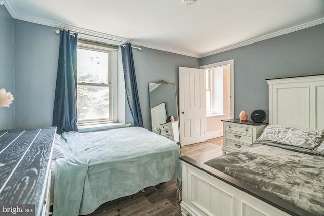 bedroom with crown molding and wood finished floors