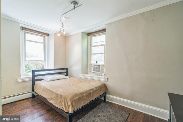 bedroom featuring crown molding, multiple windows, baseboards, wood finished floors, and a baseboard heating unit