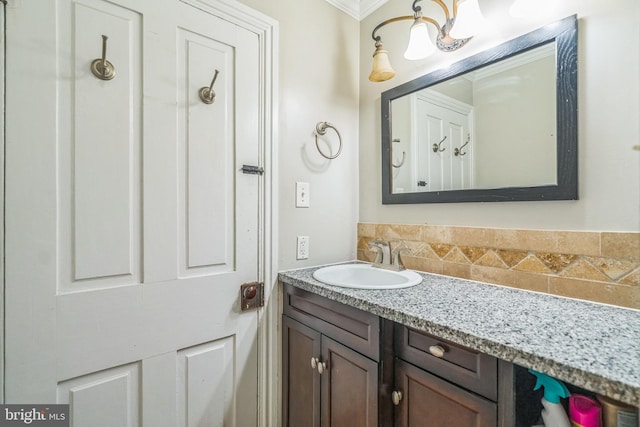 bathroom featuring backsplash, ornamental molding, and vanity