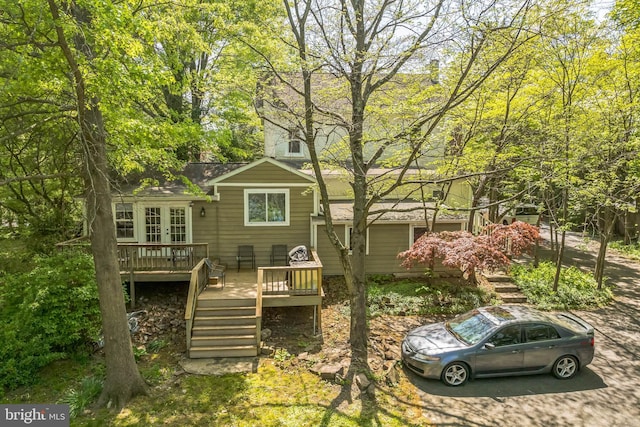 back of house featuring a deck, a shingled roof, french doors, and stairs