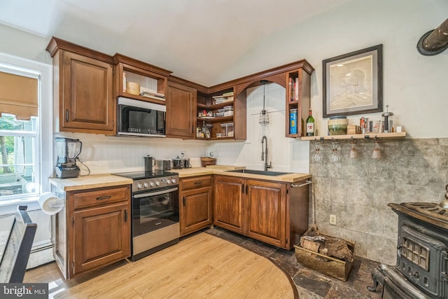 kitchen featuring open shelves, a wood stove, vaulted ceiling, a sink, and stainless steel appliances