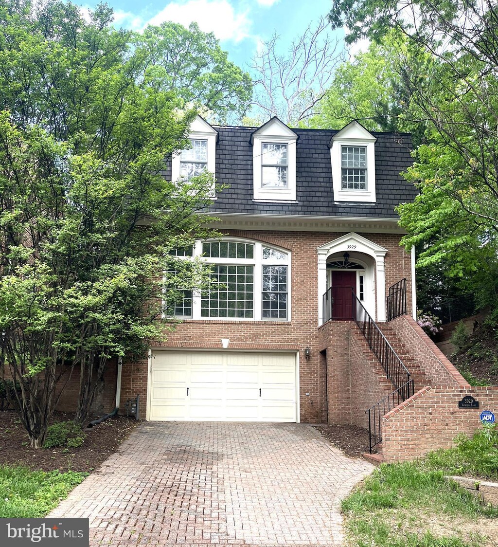 cape cod-style house featuring an attached garage, decorative driveway, and brick siding