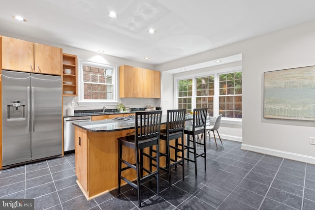 3929 Vacation Ln, Arlington, VA 22207 - kitchen featuring stainless steel appliances, a sink, dark tile patterned flooring, a kitchen bar, and dark stone countertops