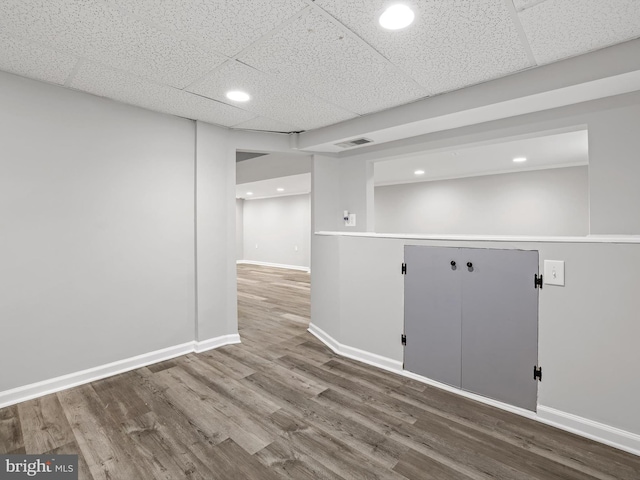 finished basement with visible vents, wood finished floors, baseboards, a drop ceiling, and recessed lighting