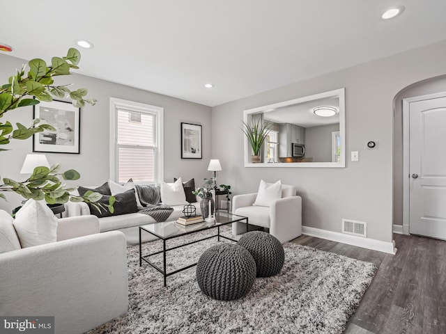 living area with arched walkways, recessed lighting, baseboards, wood finished floors, and visible vents