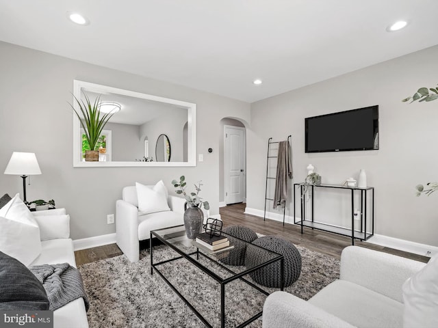living area with arched walkways, baseboards, recessed lighting, and wood finished floors