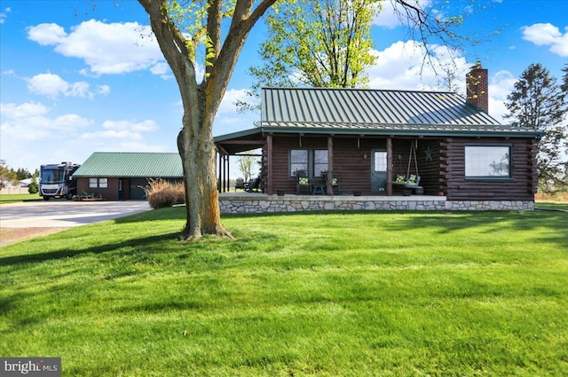 back of property with a yard, a standing seam roof, log exterior, and a chimney