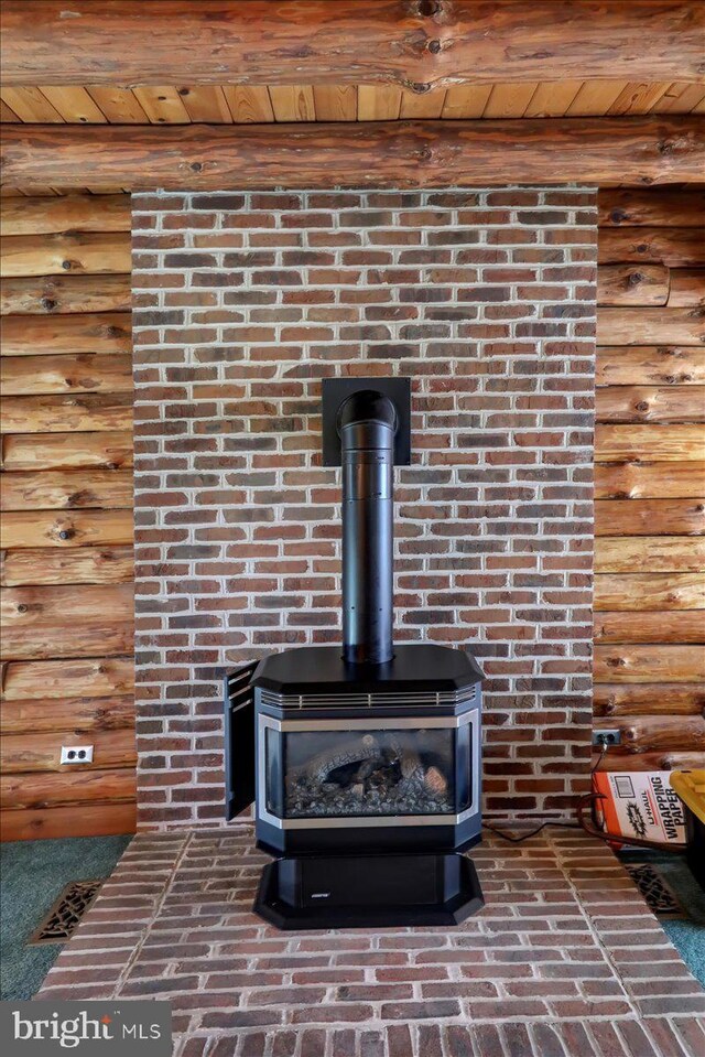 room details with beamed ceiling, wood ceiling, a wood stove, and rustic walls