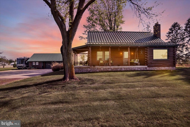 log home with covered porch, log exterior, a chimney, and a front lawn