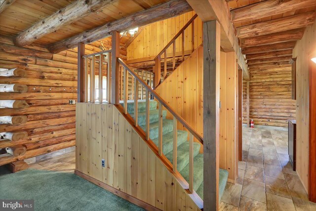 staircase featuring wooden ceiling, beamed ceiling, and log walls