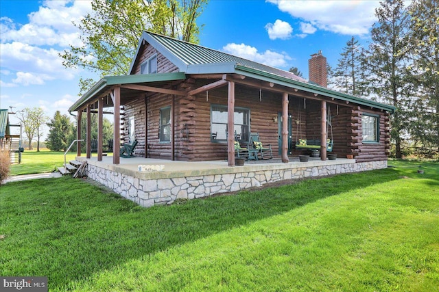 exterior space featuring log exterior, a chimney, metal roof, and a front yard