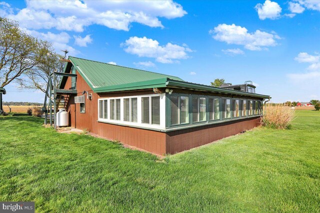 view of home's exterior with a sunroom, a yard, metal roof, and stairway