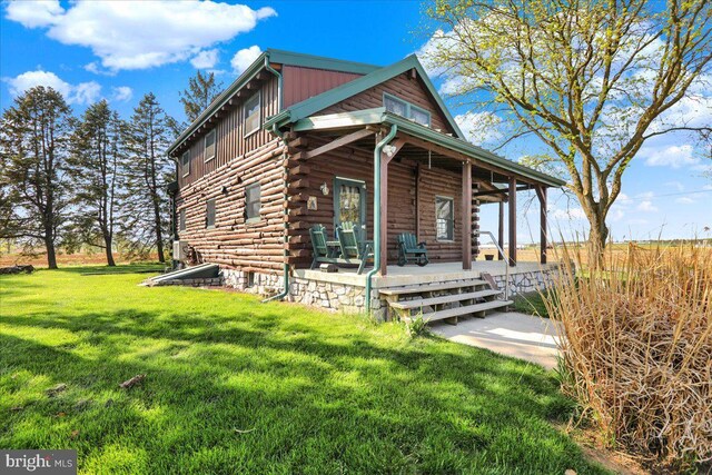 view of front of house with log exterior, a porch, and a front lawn