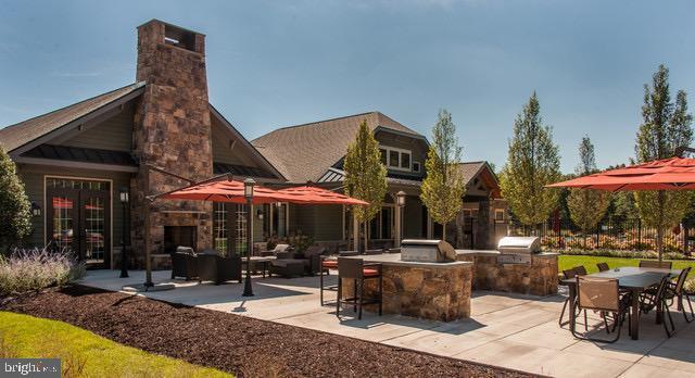 back of property featuring a standing seam roof, a chimney, a patio, an outdoor kitchen, and outdoor dining space