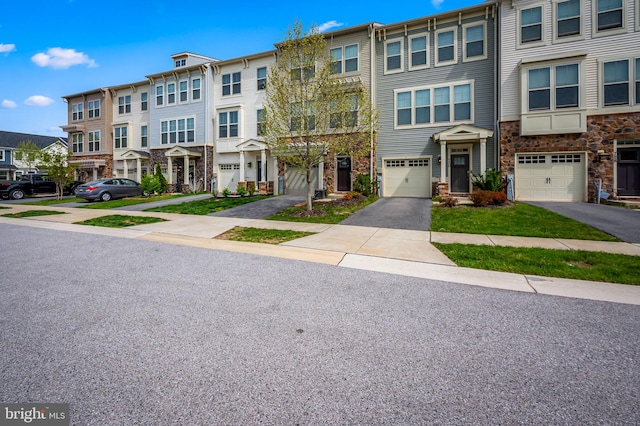 townhome / multi-family property featuring a residential view, an attached garage, driveway, and stone siding