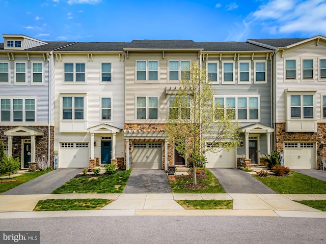 multi unit property with an attached garage, driveway, and stone siding