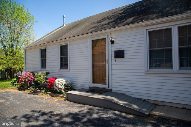 entrance to property featuring a shingled roof
