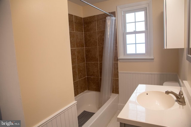 full bathroom featuring vanity, a wainscoted wall, and shower / bath combo