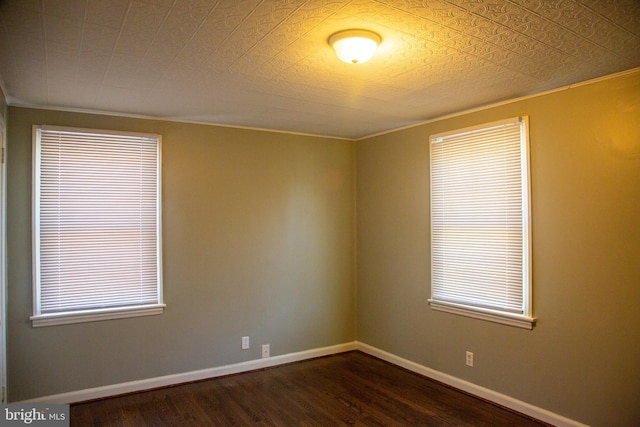 empty room with crown molding, baseboards, and dark wood-style floors