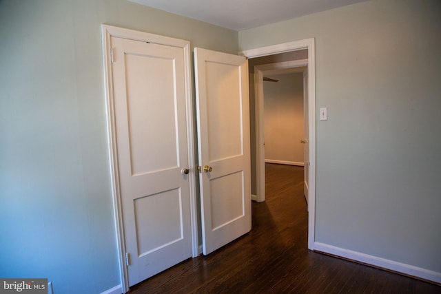 corridor featuring baseboards and dark wood-style floors