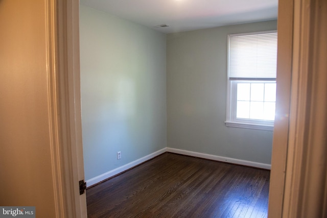 empty room with baseboards, dark wood-style floors, and visible vents