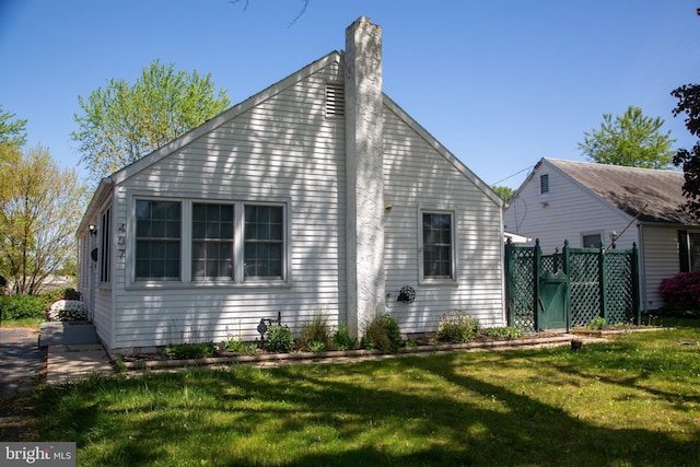 back of property with a lawn, fence, and a chimney