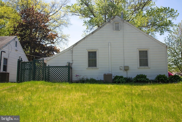 view of side of home with a yard and central AC