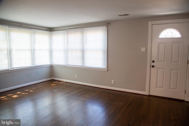 foyer featuring baseboards, wood finished floors, and visible vents