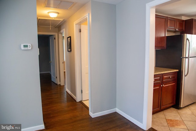 corridor featuring visible vents, attic access, baseboards, and light wood-style floors