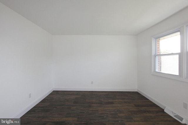 empty room with visible vents, dark wood-style flooring, and baseboards