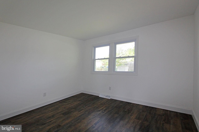 spare room featuring baseboards and dark wood finished floors