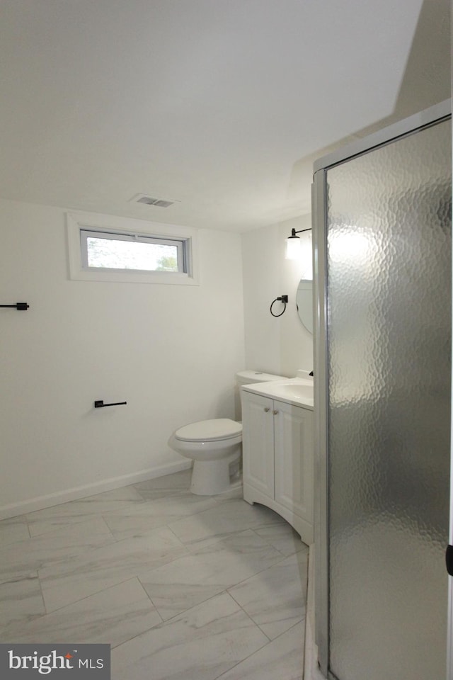 bathroom featuring vanity, marble finish floor, toilet, baseboards, and a stall shower