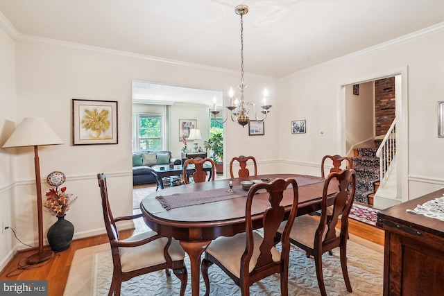 dining room featuring crown molding, baseboards, light wood-style floors, a chandelier, and stairs