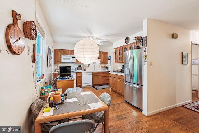 kitchen featuring a ceiling fan, white appliances, light countertops, and light wood-style floors
