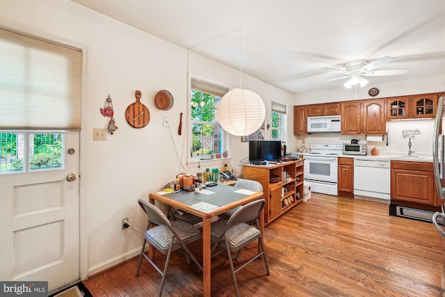 kitchen with ceiling fan, brown cabinetry, a healthy amount of sunlight, and white appliances