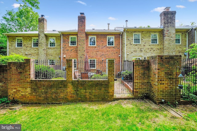 rear view of property with fence, brick siding, a yard, and a chimney