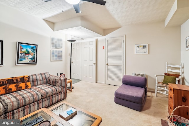 living area with ceiling fan, a textured ceiling, carpet flooring, and baseboards