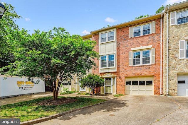 townhome / multi-family property featuring an attached garage, brick siding, and driveway