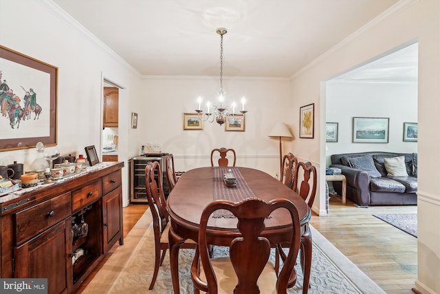 dining area with wine cooler, ornamental molding, a chandelier, and light wood-type flooring