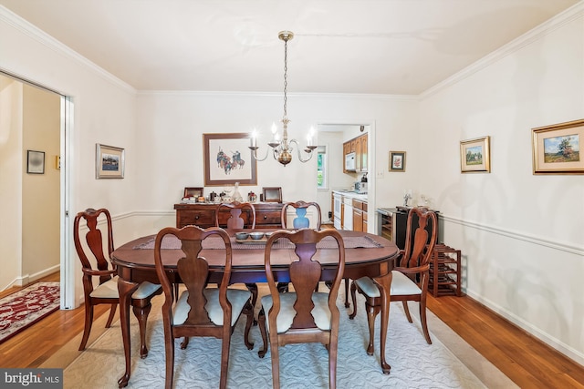 dining area featuring crown molding, light wood-style flooring, baseboards, and a notable chandelier