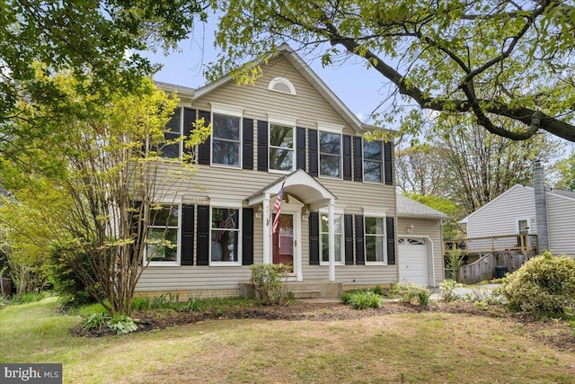 colonial home featuring a front lawn, a sunroom, and a garage