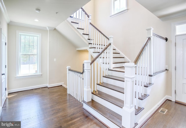 stairway with ornamental molding, wood finished floors, and visible vents