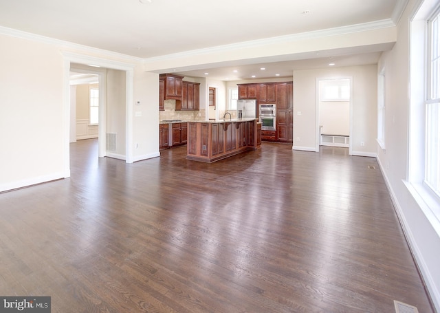unfurnished living room with baseboards, plenty of natural light, and dark wood-style floors
