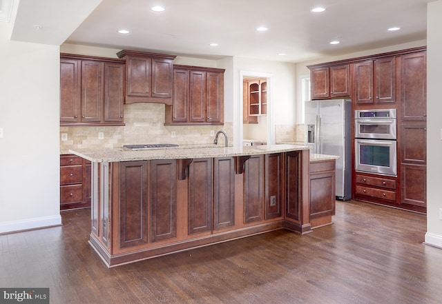 kitchen featuring a kitchen island with sink, stainless steel appliances, recessed lighting, backsplash, and dark wood-style floors