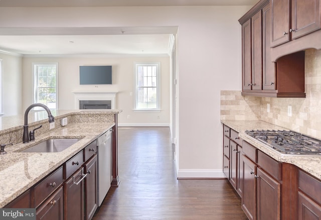 kitchen with a sink, dark wood finished floors, baseboards, stainless steel gas stovetop, and ornamental molding