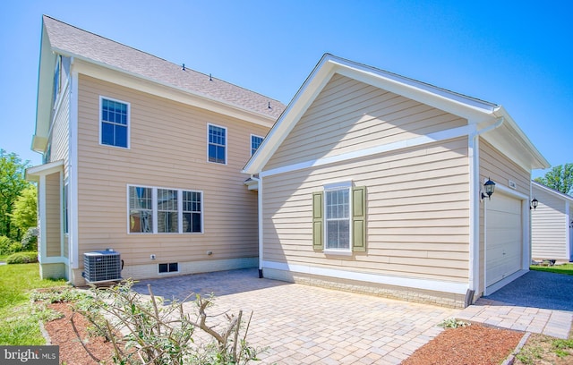 back of house featuring an attached garage, cooling unit, a patio area, and aphalt driveway
